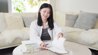 Asyalı kadın bir referans kitabıyla çalışıyor.