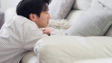 Kanepede depresif bir Asyalı var.