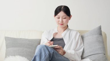 Asyalı kadın evde fikirleri not alıyor.