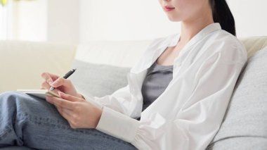 Asyalı kadın evde fikirleri not alıyor.