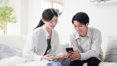 Akıllı telefona bakan gülümseyen Asyalı çift