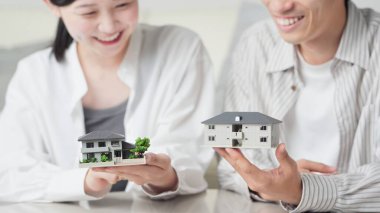 Ayrılmış ev ve apartmanı karşılaştıran Asyalı bir çift.