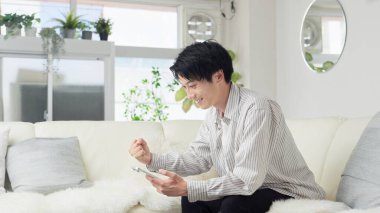 Asyalı adam akıllı telefona bakıyor ve yumruk pompası yapıyor.