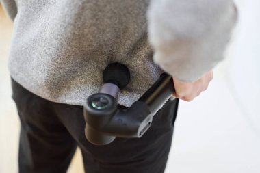 Sırtına masaj tabancası takan Asyalı bir adam.