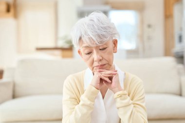 Asyalı son sınıf öğrencisi kadın oturma odasında dirseklerinin üzerinde dinleniyor.