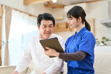 Evde bakıcılık yapan bir bakıcı tablet kullanır.