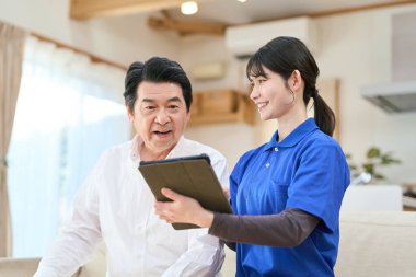 Evde bakıcılık yapan bir bakıcı tablet kullanır.