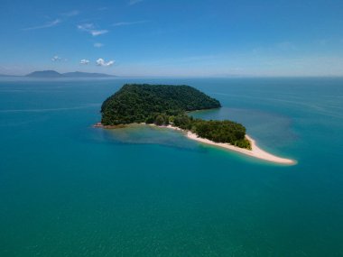 Besut, Terengganu 'da Pantai Bukit Keluang açıklarındaki küçük bir tropikal adanın havadan görünüşü. Ada yoğun yeşil ormanlarla kaplı ve canlı turkuaz sularla çevrili..