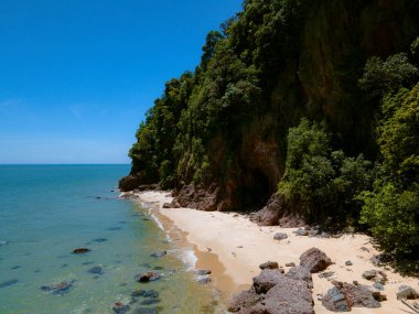 Pantai Bukit Keluang, Besut, Terengganu 'nun hava manzarası turkuaz suları, kıyı kayalıkları ve kıyı şeridi boyunca güneşli gökyüzünü gösteriyor..