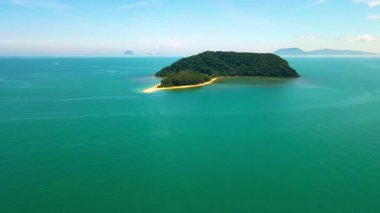 Besut, Terengganu 'da Pantai Bukit Keluang açıklarındaki küçük bir tropikal adanın havadan görünüşü. Ada yoğun yeşil ormanlarla kaplı ve canlı turkuaz sularla çevrili..