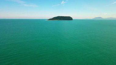 Besut, Terengganu 'da Pantai Bukit Keluang açıklarındaki küçük bir tropikal adanın havadan görünüşü. Ada yoğun yeşil ormanlarla kaplı ve canlı turkuaz sularla çevrili..
