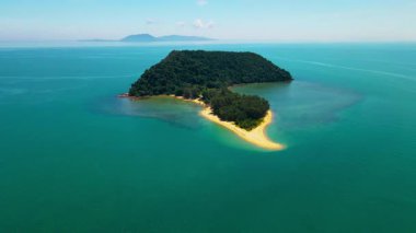 Besut, Terengganu 'da Pantai Bukit Keluang açıklarındaki küçük bir tropikal adanın havadan görünüşü. Ada yoğun yeşil ormanlarla kaplı ve canlı turkuaz sularla çevrili..
