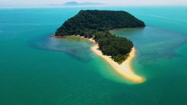 Besut, Terengganu 'da Pantai Bukit Keluang açıklarındaki küçük bir tropikal adanın havadan görünüşü. Ada yoğun yeşil ormanlarla kaplı ve canlı turkuaz sularla çevrili..