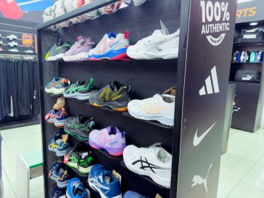 Rawang, Selangor, Malezya - 27 Kasım 2025 - spor mağazası rafı çeşitli spor ayakkabılarını çeşitli renklerde sergiliyor yan panelde logolar görünüyor.