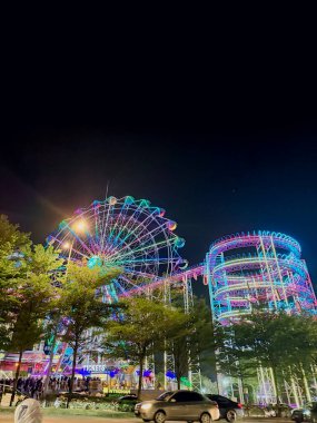 Shah Alam, Selangor, Malezya - 4 Aralık 2025 - Parlak dönme dolabı ve renkli ışıklarla kalabalıkları çeken eğlenceli bir gece sahnesi.