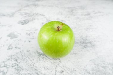 Açık dokulu yüzeyde izole edilmiş taze yeşil elma. Diyet, beslenme, temiz yeme ve organik gıda temaları için sağlıklı meyve konsepti.
