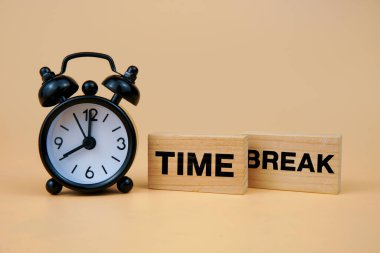 Çalar saat ve tahta bloklarla mola zamanı kavramı TIME BREAK, dinlenme periyodunu sembolize eder, duraklat, iş-yaşam dengesi, verimlilik sıfırlama ve zihinsel sağlığı simgeler..