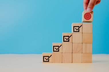 Kurumsal düzenleme ve uyum. Hedefler başarı ve iş başarısı. Proje ve hedefler izliyor. Görev tamamlanmıştır. Proje zaman çizelgesi yönetiliyor. Hedef başarı simgesiyle tahta küp tutuluyor.