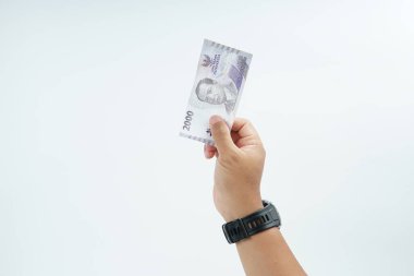 Beyaz zemin üzerinde el ele tutuşan Endonezya rupiah banknotu nakit ödeme, kişisel finans, gelir ve temiz minimum kompozisyon ile mali işlemleri temsil ediyor.