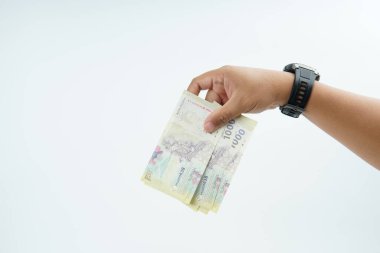 Beyaz zemin üzerinde el ele tutuşan Endonezya rupiah banknotu nakit ödeme, kişisel finans, gelir ve temiz minimum kompozisyon ile mali işlemleri temsil ediyor.