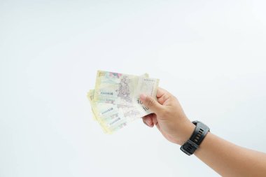 Beyaz zemin üzerinde el ele tutuşan Endonezya rupiah banknotu nakit ödeme, kişisel finans, gelir ve temiz minimum kompozisyon ile mali işlemleri temsil ediyor.