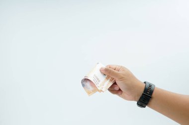 Beyaz zemin üzerinde el ele tutuşan Endonezya rupiah banknotu nakit ödeme, kişisel finans, gelir ve temiz minimum kompozisyon ile mali işlemleri temsil ediyor.