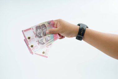 Beyaz zemin üzerinde el ele tutuşan Endonezya rupiah banknotu nakit ödeme, kişisel finans, gelir ve temiz minimum kompozisyon ile mali işlemleri temsil ediyor.