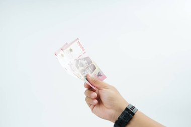 Beyaz zemin üzerinde el ele tutuşan Endonezya rupiah banknotu nakit ödeme, kişisel finans, gelir ve temiz minimum kompozisyon ile mali işlemleri temsil ediyor.