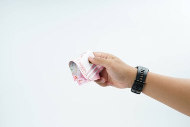 Beyaz zemin üzerinde el ele tutuşan Endonezya rupiah banknotu nakit ödeme, kişisel finans, gelir ve temiz minimum kompozisyon ile mali işlemleri temsil ediyor.