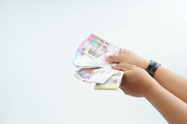 Beyaz zemin üzerinde el ele tutuşan Endonezya rupiah banknotu nakit ödeme, kişisel finans, gelir ve temiz minimum kompozisyon ile mali işlemleri temsil ediyor.