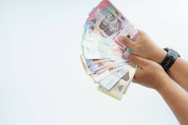 Beyaz zemin üzerinde el ele tutuşan Endonezya rupiah banknotu nakit ödeme, kişisel finans, gelir ve temiz minimum kompozisyon ile mali işlemleri temsil ediyor.