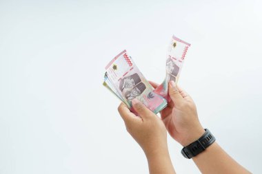 Beyaz zemin üzerinde el ele tutuşan Endonezya rupiah banknotu nakit ödeme, kişisel finans, gelir ve temiz minimum kompozisyon ile mali işlemleri temsil ediyor.