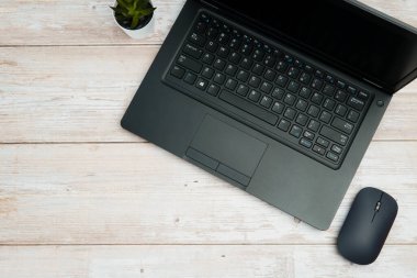 Verimliliği, dijital çalışma ortamını ve temiz kopya alanı olan profesyonel ofis kurulumunu temsil eden beyaz ahşap masa üzerine dizüstü bilgisayarı, faresi ve bitkisi olan modern iş alanının en üst görünümü.