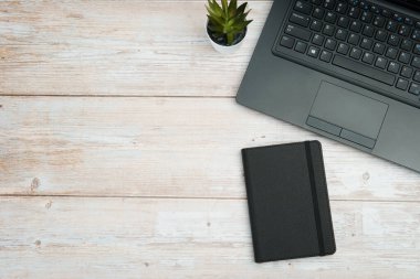 Verimliliği, planlamayı, dijital çalışma ortamını ve temiz fotokopi alanı olan profesyonel ofis ortamını temsil eden dizüstü bilgisayarlı, defterli ve beyaz ahşap masa üzerindeki işletme çalışma alanının en üst görünümü.