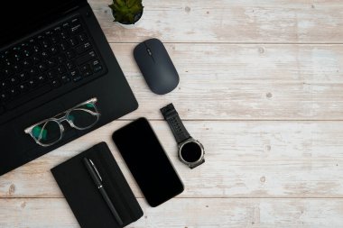 Dizüstü bilgisayarlı, akıllı telefonlu, gözlüklü, not defterli, fareli ve üretkenliği, dijital çalışmayı ve temiz kopya alanı olan profesyonel ofis kurulumunu temsil eden beyaz ahşap masadaki çalışma alanı.