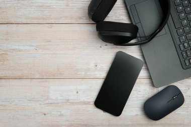 Bilgisayarlı, akıllı telefonlu, fareli, kulaklıklı ve beyaz ahşap masadaki kahve ile en üst düzey çalışma alanı üretkenliği, uzaktan çalışmayı, dijital odağı ve temiz kopya alanı olan profesyonel ofis ortamını temsil ediyor..