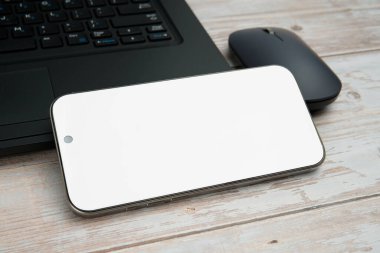 Üst görünüm iş alanı dizüstü bilgisayarı, boş akıllı telefonu, faresi ve beyaz ahşap masa üzerine bitkisi verimliliği, dijital işi, model görüntüsünü ve temiz kopya alanı olan profesyonel ofis kurulumunu temsil ediyor..