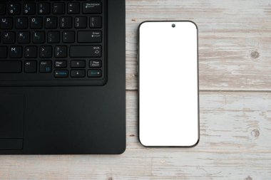 Dizüstü bilgisayarlı en iyi iş yeri, boş akıllı telefon ve üretkenliği temsil eden beyaz ahşap masa üzerine bitki, dijital çalışma, model görüntüleme ve temiz kopya alanı olan profesyonel ofis kurulumu.