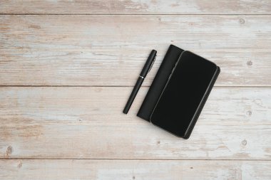 Planlama, yazma, iş notlarını, üretkenlik, organizasyon, asgari çalışma alanı ve kopyalama alanını temsil eden beyaz ahşap arkaplan üzerine düz bir defter ve kalem..