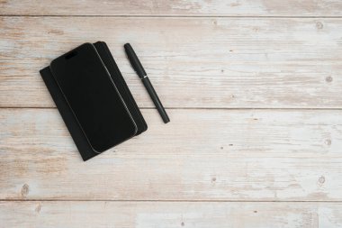 Planlama, yazma, iş notlarını, üretkenlik, organizasyon, asgari çalışma alanı ve kopyalama alanını temsil eden beyaz ahşap arkaplan üzerine düz bir defter ve kalem..