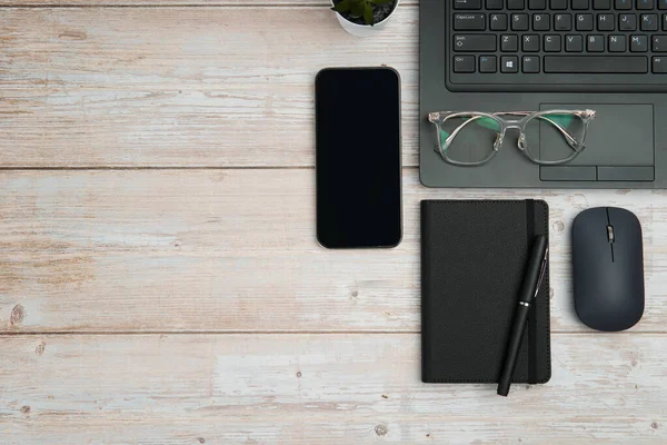 Dizüstü bilgisayarlı, akıllı telefonlu, gözlüklü, defterli ve fareli en iyi iş yeri beyaz ahşap masadaki verimliliği, dijital çalışmayı ve temiz kopya alanı olan profesyonel ofis ortamını temsil ediyor..