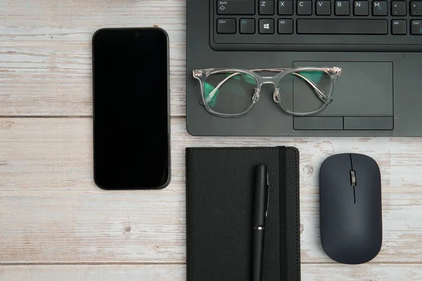 Dizüstü bilgisayarlı, akıllı telefonlu, gözlüklü, defterli ve fareli en iyi iş yeri beyaz ahşap masadaki verimliliği, dijital çalışmayı ve temiz kopya alanı olan profesyonel ofis ortamını temsil ediyor..