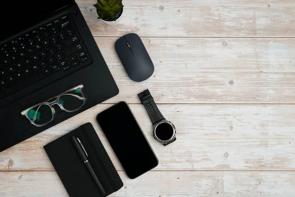 Dizüstü bilgisayarlı, akıllı telefonlu, gözlüklü, not defterli, fareli ve üretkenliği, dijital çalışmayı ve temiz kopya alanı olan profesyonel ofis kurulumunu temsil eden beyaz ahşap masadaki çalışma alanı.