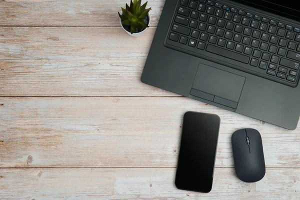 Üst görünüm minimal iş alanı dizüstü bilgisayarı, akıllı telefonu, faresi ve beyaz ahşap masa üzerine bitkisi ile verimliliği temsil eden, dijital çalışma ortamı, ve temiz kopya alanı ile profesyonel ofis kurulumu.