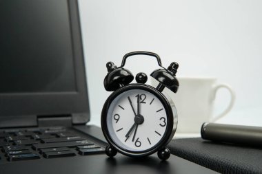 Not defteri, kalem ve kahve fincanının yanında siyah alarmlı ofis çalışma alanı. Zaman yönetimi kavramı, verimlilik, verimlilik, odaklanma, dakiklik ve profesyonel rutin.