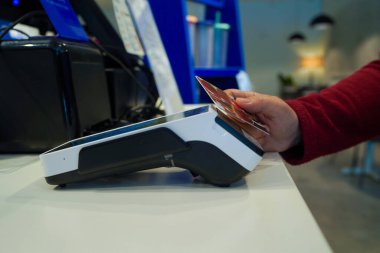 Tezgahtaki ödeme makinesine el ile dokunmak, nakit ödemeyi temsil etmek, fintech teknolojisi, kart işlemi, perakende hesabı ve dijital finans kavramını temsil etmek.