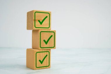 Mermer arkaplan, görev tamamlama ve kalite onaylama kavramına yeşil işaretli ahşap küpleri yığıldı.