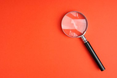 Kırmızı arkaplanda kopya alanı olan büyüteç, arama, keşif, soruşturma ve bilgi bulma kavramını temsil ediyor.