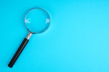 Mavi arkaplanda kopya alanı olan büyüteç, arama, analiz, soruşturma ve bilgi keşfi kavramını temsil ediyor.