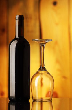bottle with wine and an inverted glass on a background of wooden boards